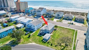 A coastal residential area with houses, a road, and a beach in the background.