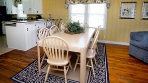 Un comedor con mesa y sillas, una cocina al fondo y una sala de estar con sofá.
