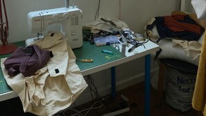 A sewing room with a sewing machine, a window with a view of brick buildings, a lamp, and various sewing materials on a table. - Charming 3-bed Apartment in London (London)