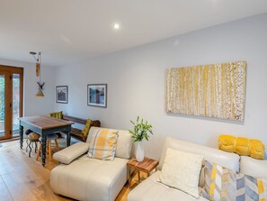 Un salon moderne avec un canapé, une table à manger et une table basse. Des tableaux encadrés ornent le mur et une plante est posée sur la table basse.