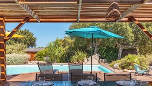 An outdoor dining area with a pool and wooden pergola. - Villa Calyaunati Di San Ciprianu (Lecci)