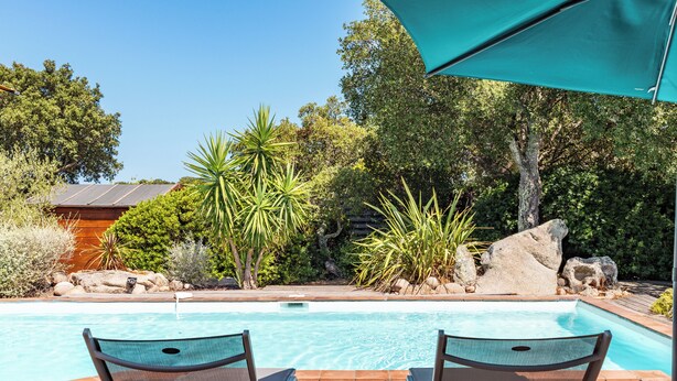 A pool area with two lounge chairs and a large umbrella. - Villa Calyaunati Di San Ciprianu (Lecci)