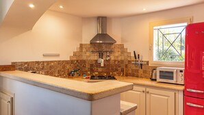 A kitchen with a central island, a stove, a microwave, and a red refrigerator. - Villa Calyaunati Di San Ciprianu (Lecci)