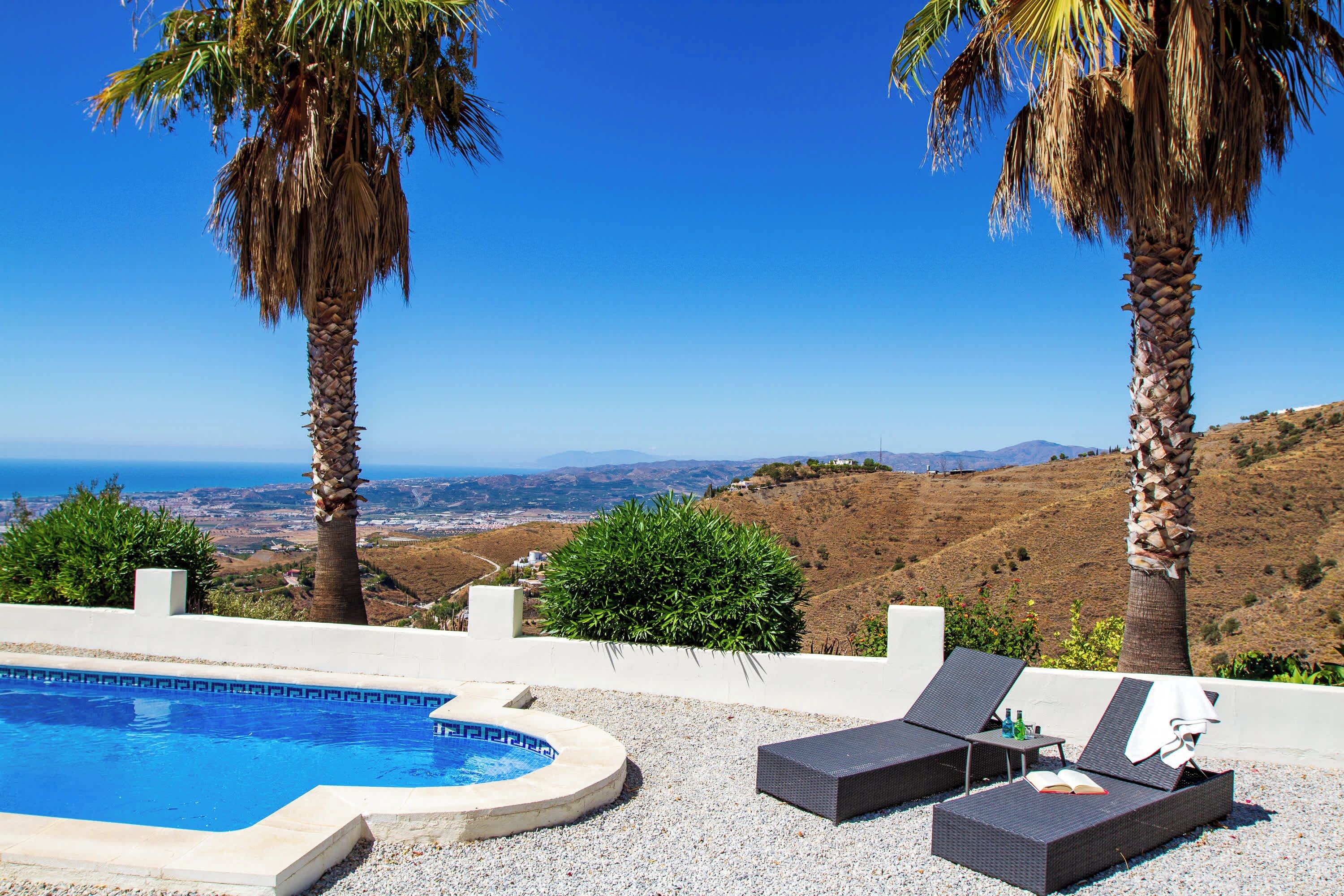 A pool area with lounge chairs and a view of the landscape.