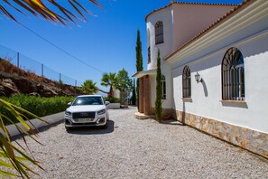 A white building with a gravel driveway, a parked car, and a clear blue sky.