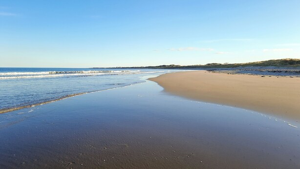 A beach with a wide sandy shore and gentle waves. - Och Moo at Number 47 (Seahouses)