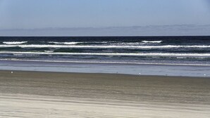 Ein Strand mit Wellen, sandigem Ufer und blauem Himmel.