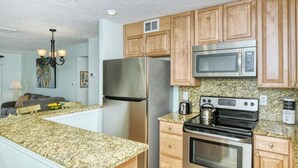 Una cocina con encimeras de granito, electrodomésticos de acero inoxidable, armarios de madera y horno empotrado.
