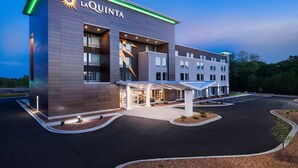 Um hotel moderno com um grande letreiro 'La Quinta', entrada coberta e estacionamento.