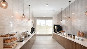 Uma cozinha moderna com bancada comprida, máquinas de café e dispensadores de alimentos.