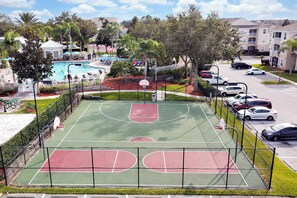 Un terrain de basket avec une piscine et un parking.