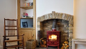 A cozy room with a stone fireplace, a wooden rocking chair, and a bookshelf. - 1 bedroom accommodation in Kirkby Lonsdale (Kirkby Lonsdale)