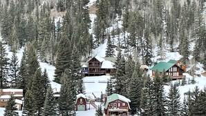 A snow-covered mountain lodge with multiple cabins surrounded by dense evergreen trees. - Red River, NM Upper Valley Mountainside Retreat (Red River)