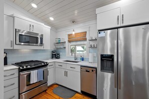 Una cocina moderna con electrodomésticos de acero inoxidable, armarios blancos y lavavajillas integrado.