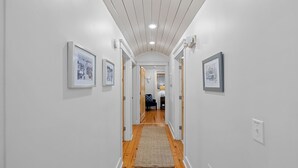 En hall med vita väggar, trägolv och inramade tavlor på väggarna.
