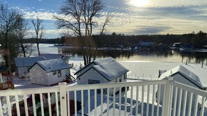 Una cubierta nevada con vista a un lago y casas al fondo.