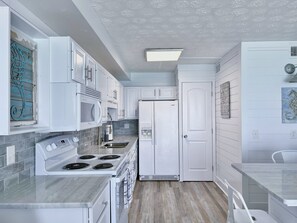 A modern kitchen with white cabinets, a built-in microwave, a stove, and a refrigerator.