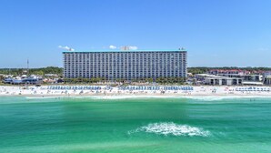 Un grand hôtel à plusieurs étages, avec une plage en premier plan.