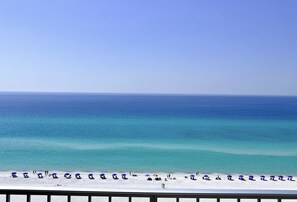 A beach with rows of blue umbrellas and white sand.