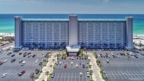 Un grand hôtel à plusieurs étages, doté d’une cour intérieure et d’un parking où sont stationnées plusieurs voitures.
