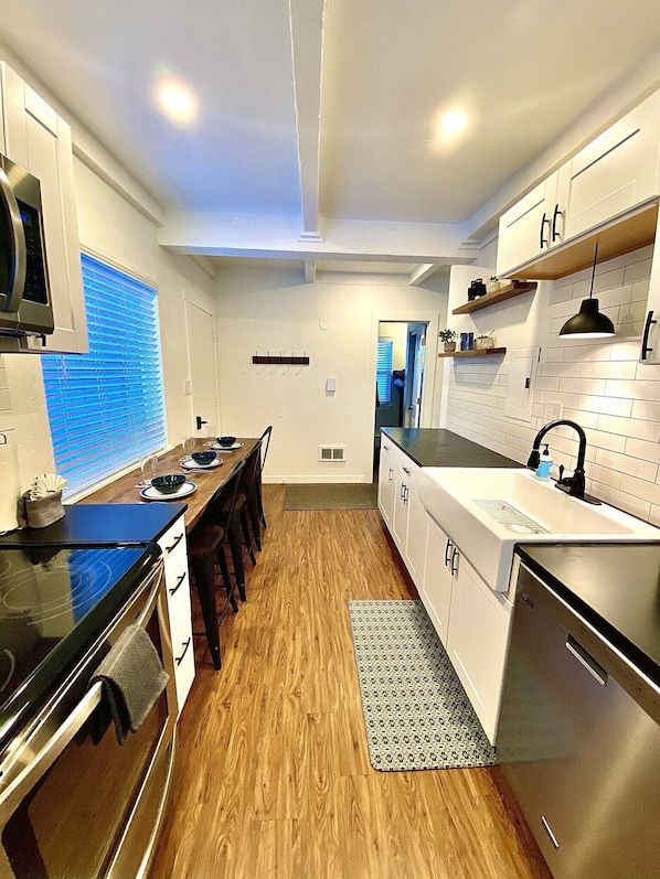 A modern kitchen with white cabinetry, a wooden dining table, and a built-in oven. - 26/27 El Nino Winter Basecamp! Fully stocked, fresh design, private condo! (Silverthorne)