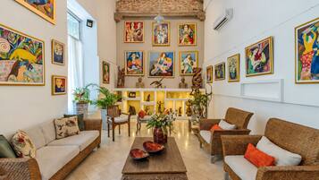 A spacious living room with a high ceiling, multiple seating areas, and a variety of artwork on the walls.