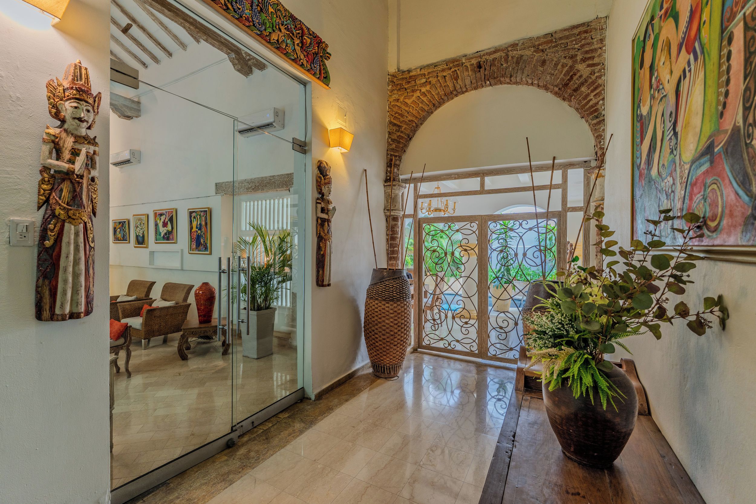 A modern interior with a glass door entrance, a seating area with chairs, and a large potted plant.