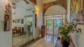 A modern interior with a glass door entrance, a seating area with chairs, and a large potted plant.