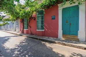 Une rue avec un bâtiment rouge, une porte verte et un arbre aux feuilles vertes.