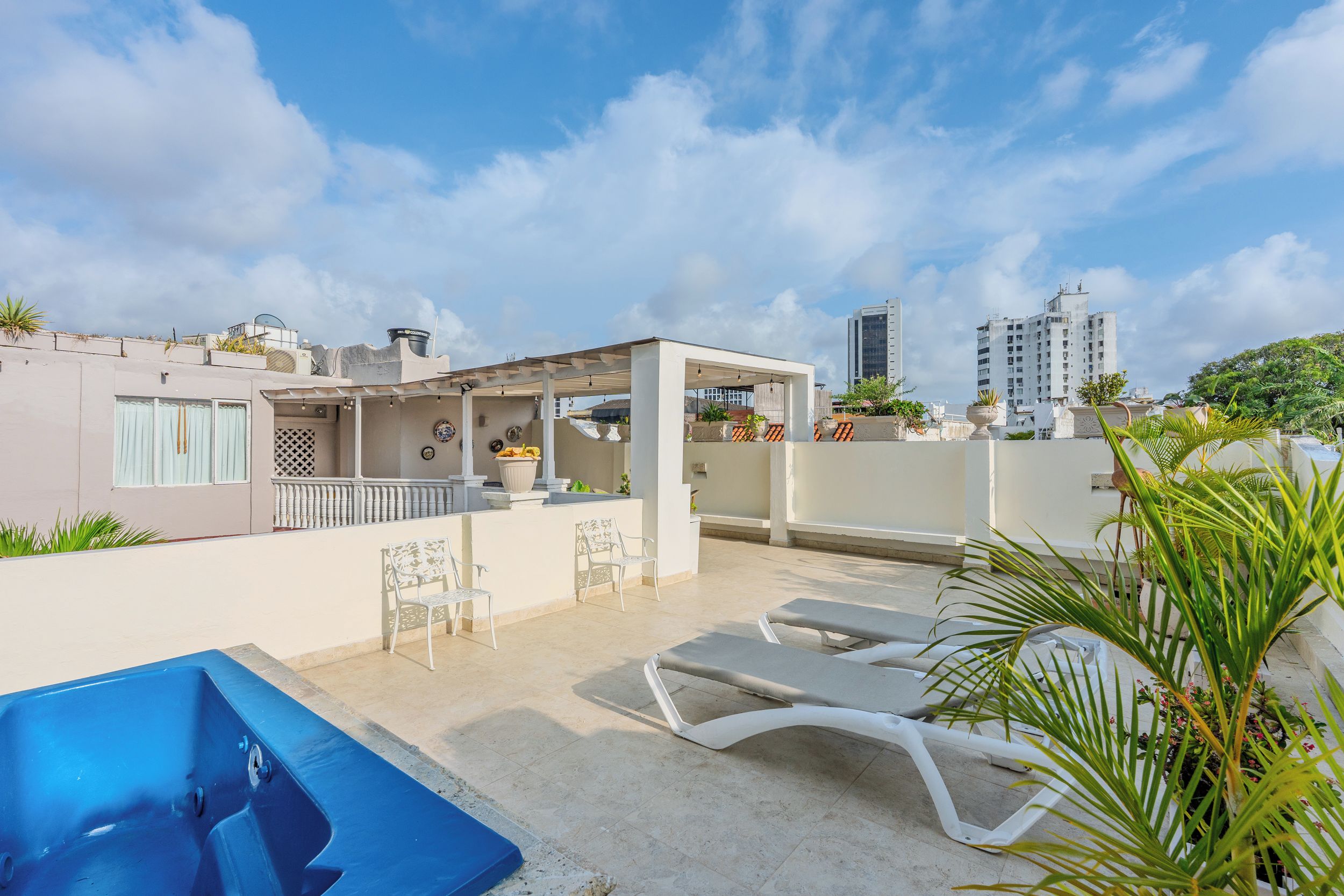A rooftop terrace with a pool, lounge chairs, and a covered seating area.