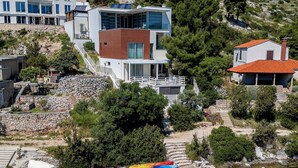 Uma casa moderna de dois andares com uma escadaria de pedra que leva a um deck de madeira.