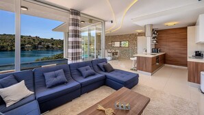 Uma sala de estar moderna com um amplo sofá em formato de L, uma mesa de centro e vista para um lago.