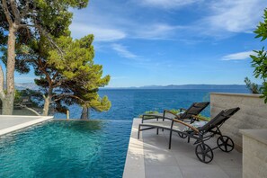 Ein Poolbereich mit Liegestühlen und Meerblick.