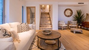 Un salon moderne avec un escalier, des meubles blancs et une table basse en bois.