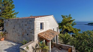 Un bâtiment en pierre avec un toit en tuiles, une petite fenêtre et une vue sur la mer.