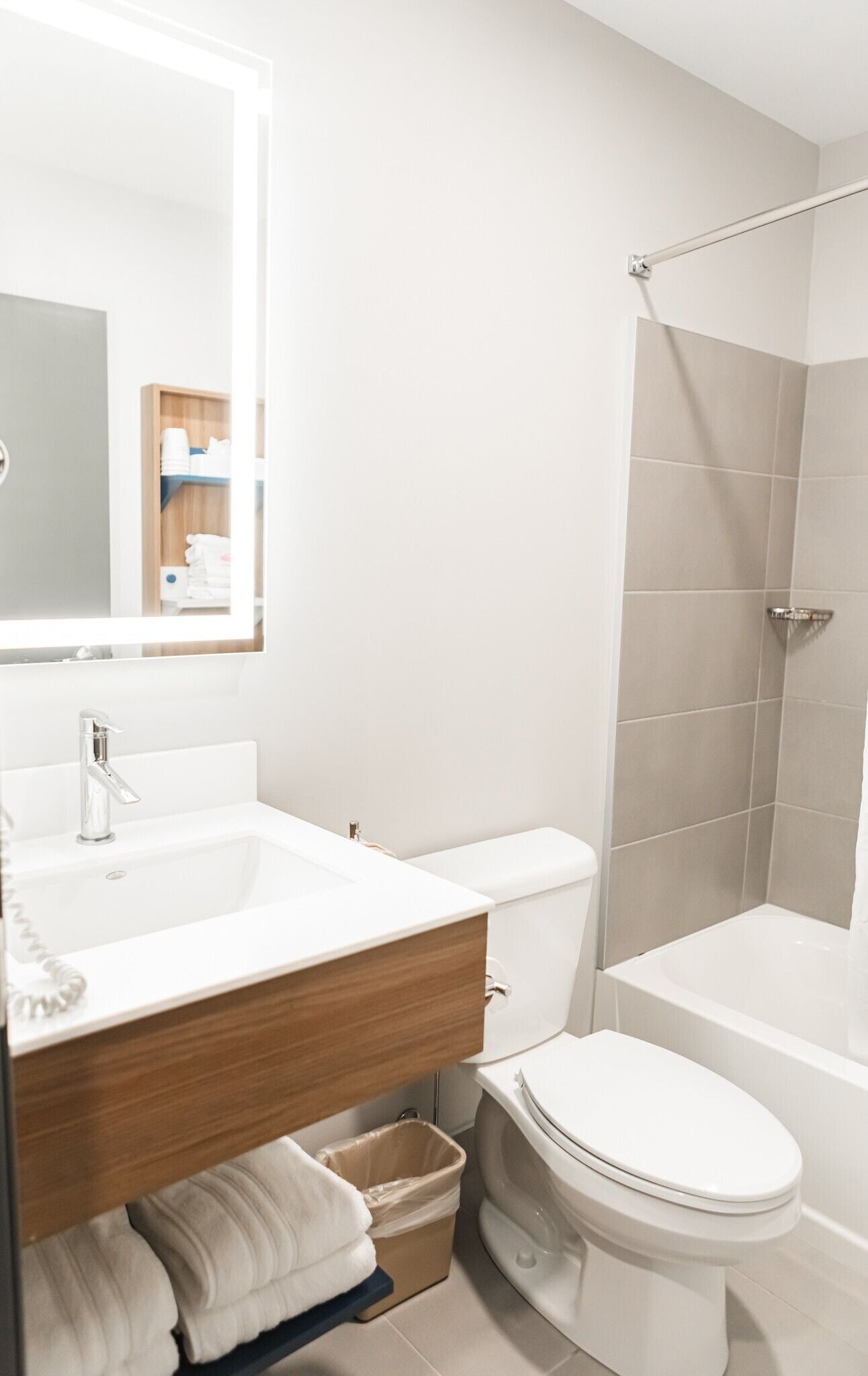A modern bathroom with a white sink, mirror, and toilet.