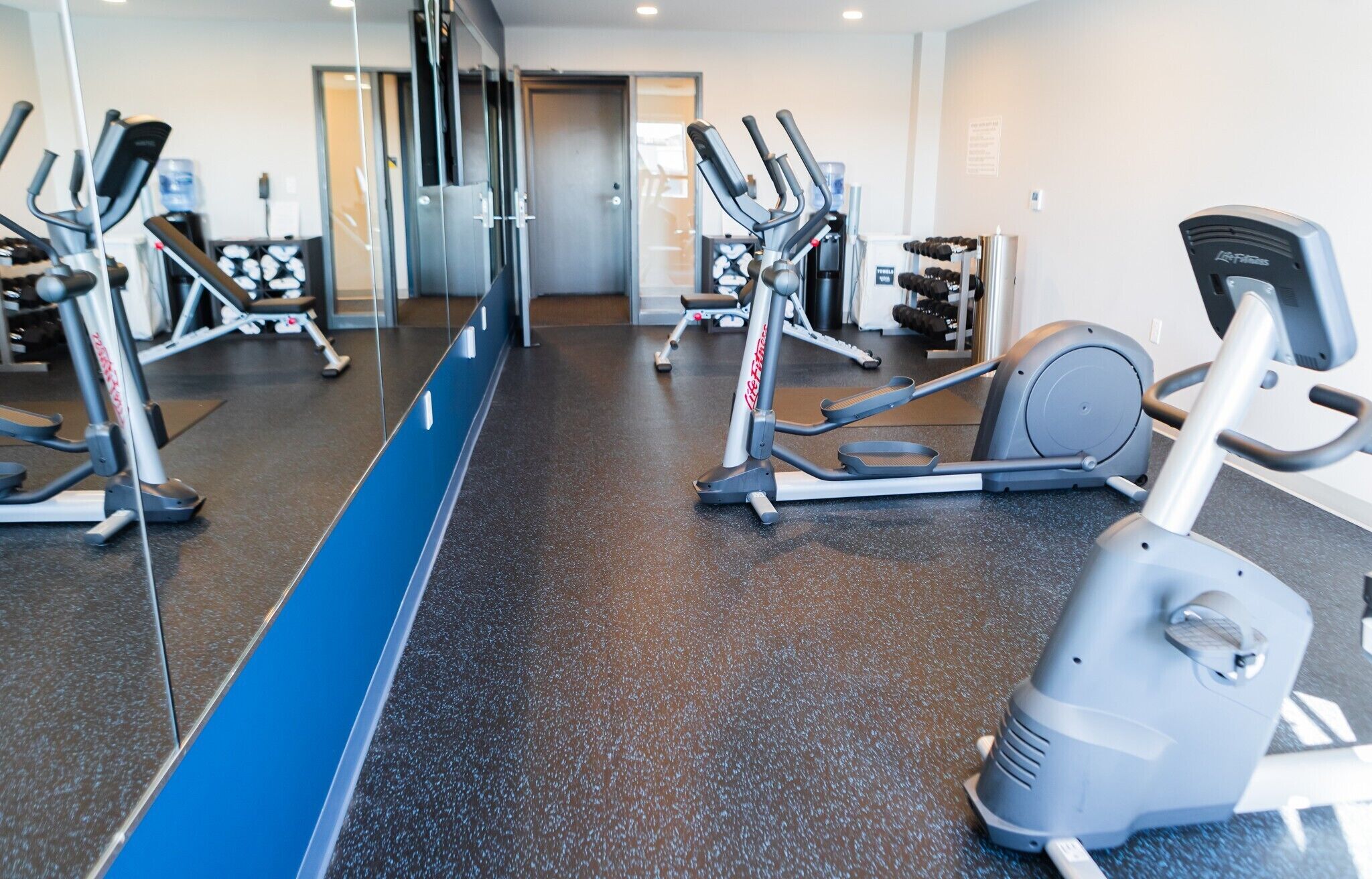 A gym with various exercise equipment, including treadmills and elliptical machines.