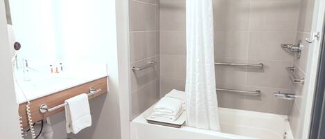 Une salle de bain moderne équipée d’une baignoire, d’une douche et d’un meuble-lavabo.