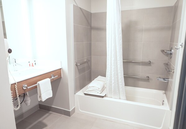 A modern bathroom with a bathtub, shower, and vanity.