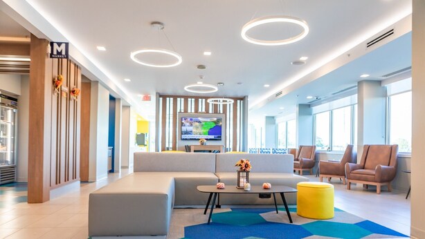 A modern lobby with a large sofa, seating area, and a television. - Microtel Inn & Suites by Wyndham Milford (Milford)