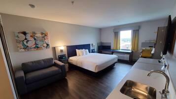 Une chambre d’hôtel équipée d’un lit, d’un canapé, d’un bureau, d’une télévision et d’un lavabo.
