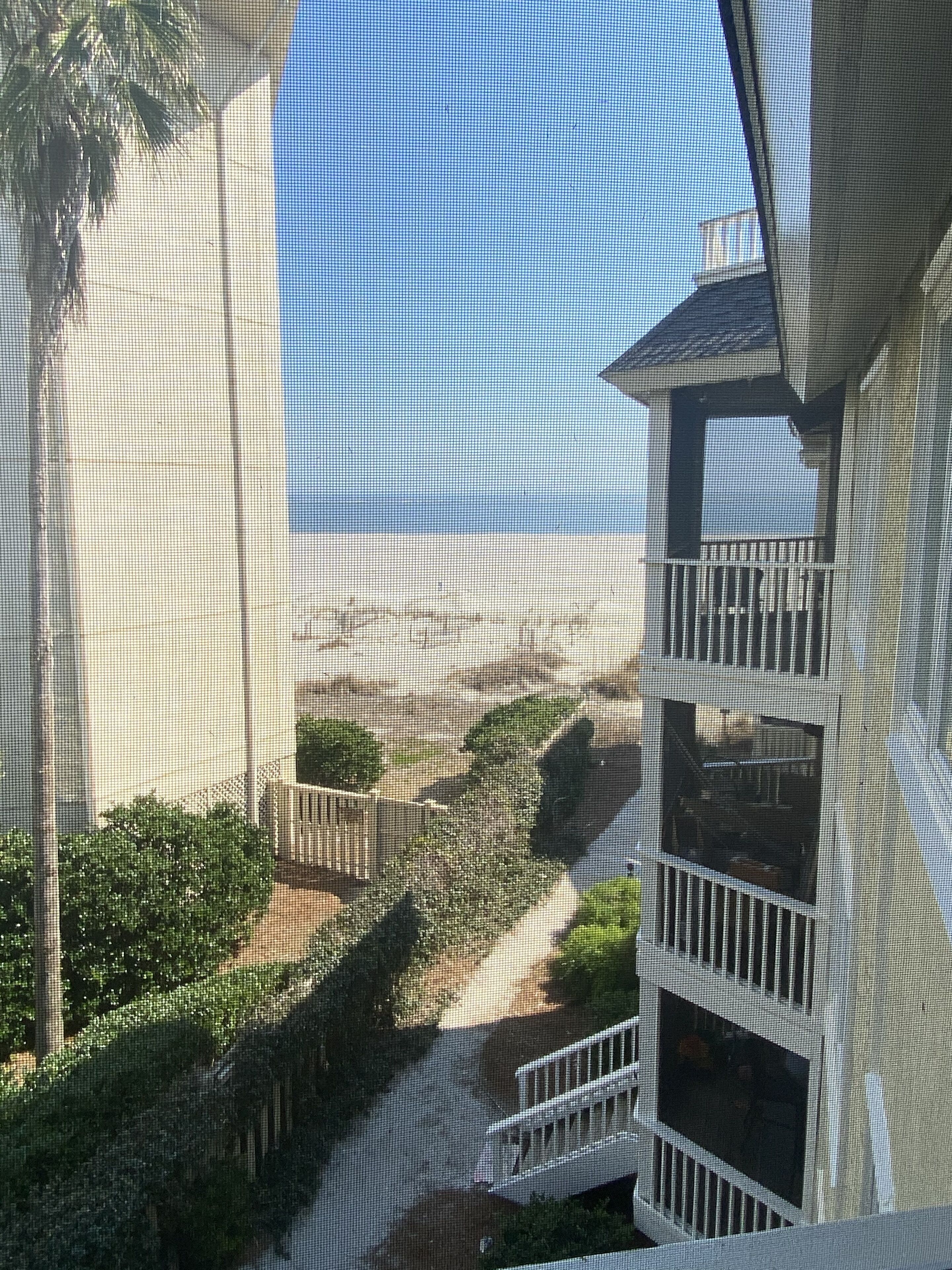 A view from a balcony overlooking a beach with a clear sky.