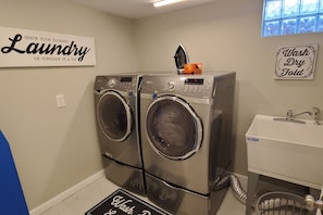 A laundry room with two front-loading washing machines, a sink, and a window. - 7006 Gail Sue · ✪☆★✪ Cindy`s Super Ranch Home ✪★☆✪ (West Chester Township)