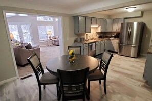 Una cocina moderna con comedor, refrigerador y vista al salón.