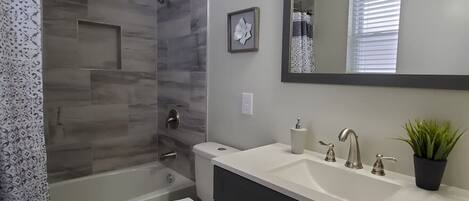 Une salle de bain équipée d’une douche, de toilettes, d’un lavabo et d’un miroir.