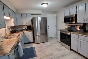 A modern kitchen with stainless steel appliances, light grey cabinets, a double sink, and a microwave. - 7006 Gail Sue · ✪☆★✪ Cindy`s Super Ranch Home ✪★☆✪ (West Chester Township)