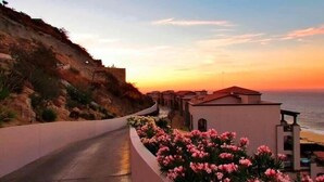 A coastal road with a curve, leading to a building with a balcony overlooking the sea. - Gorgeous 3BR Villa Perfect View at Cabo San Lucas (Cabo San Lucas)