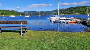 A marina with boats docked, a grassy area in the foreground, and hills in the background. - 2 bedroom accommodation in Tayvallich (Tayvallich)
