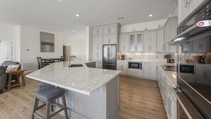 Una cocina moderna con una isla central, electrodomésticos de acero inoxidable y un comedor con mesa y sillas.