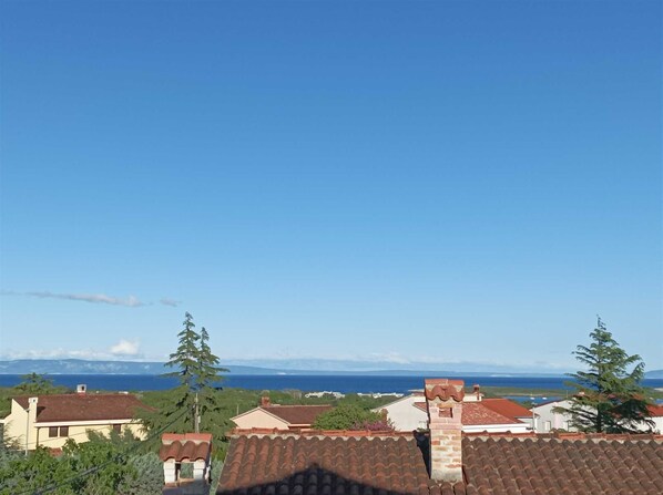 Ein Wohngebiet mit Häusern, blauem Himmel und Blick auf das Meer.